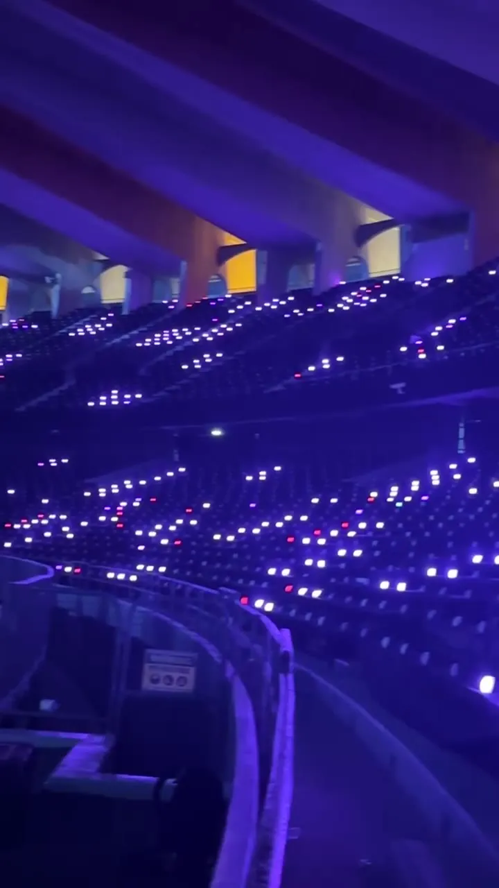 Iluminación de barandilla en una grada de estadio, con pequeños puntos de luz violeta y blanca