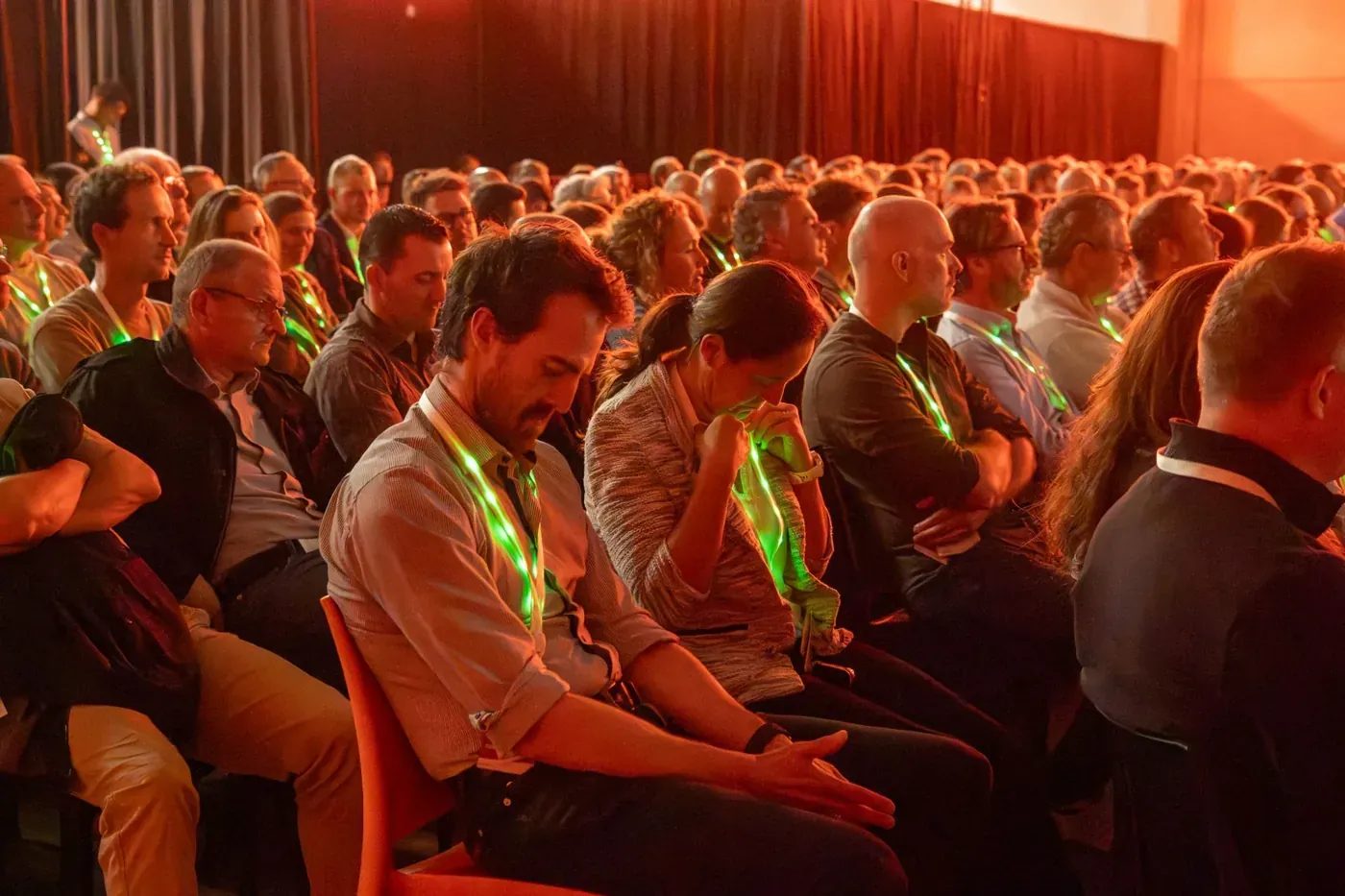 Publiek met groen opgelichte LED-lanyards tijdens een conferentie